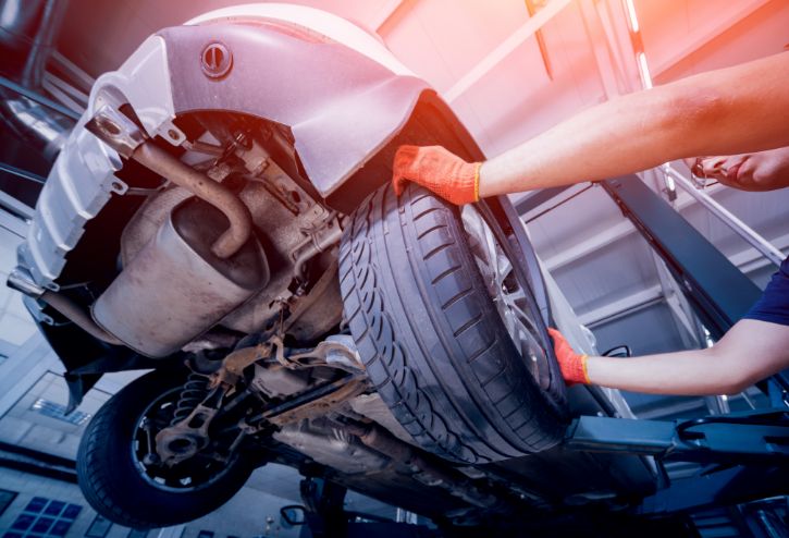 Mechanic under raised car working on a tire